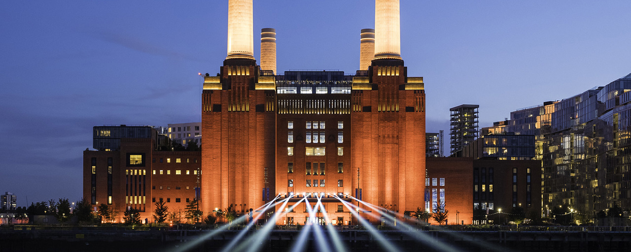 Battersea Power Station illuminated against the night sky and reflected on the Thames