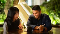 Two colleagues sitting together looking at a tablet in a plant-filled office.