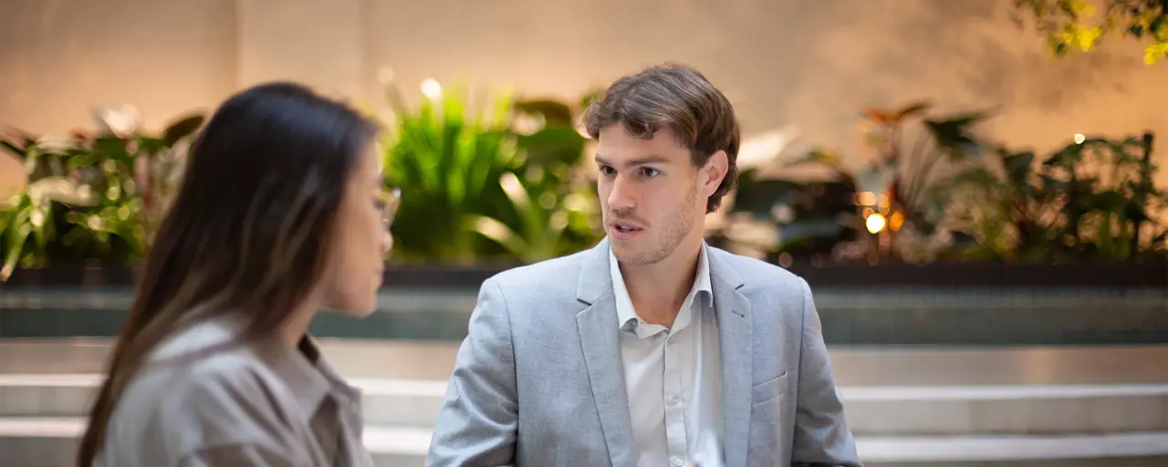 Two colleagues together having a conversation in a plant-filled office.