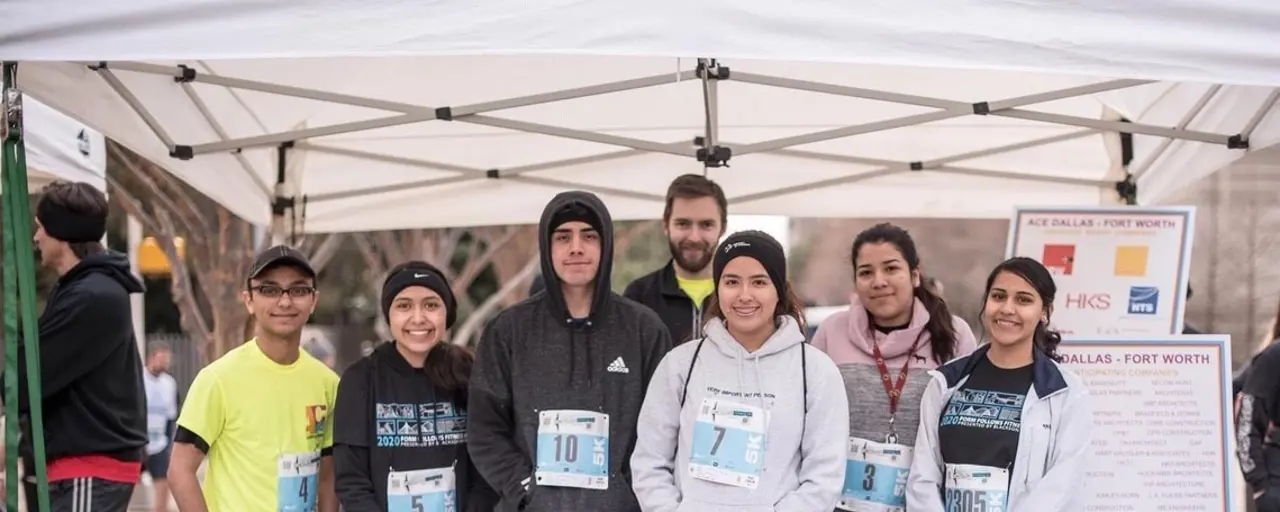 Group of 7 standing by stand promoting ACE mentor program