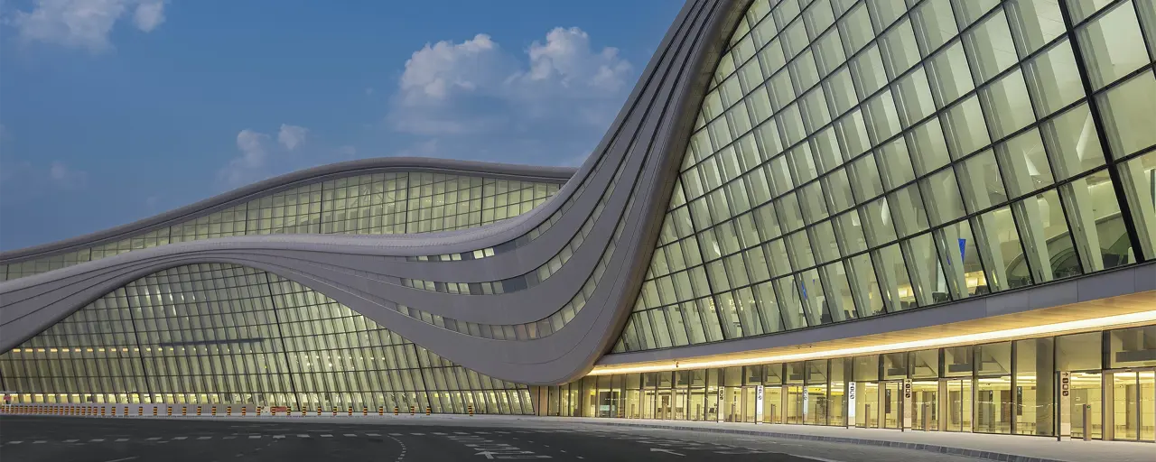 Curved glass building with yellow lights lit up inside