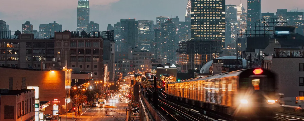 New York skyline at night with trains, skyscrapers and cars