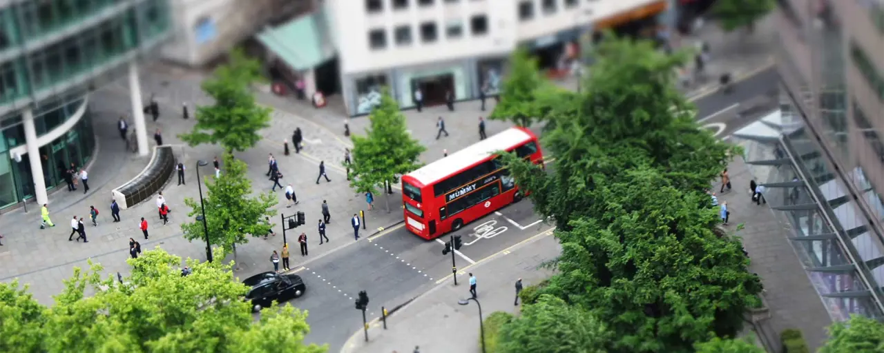 View of London city with bus going through city with pedestrians strolling through the streets. 