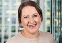 Portrait of Ashley Stewart, Project Director, with city landscape featuring building with lots of windows in the background.