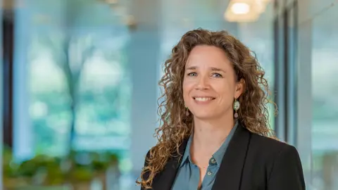 Portrait of Astrid Boumans, Director, Europe, inside a glass office with plants