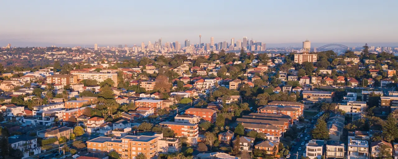 Aerial view of residential rooftops and city skyscrapers in the background