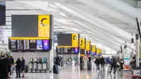 Airport with people walking through and boards showing flights.