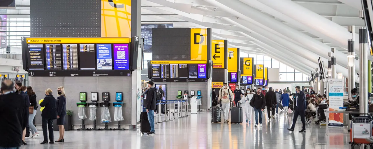 Airport with people walking through and boards showing flights.