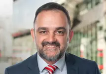 Brett Kalisch, Director, Natural Resources, Australia & New Zealand, standing outside in front of buildings featuring an urban cityscape with a mix of architectural styles. The scene includes some windows and red features, adding a touch of color.