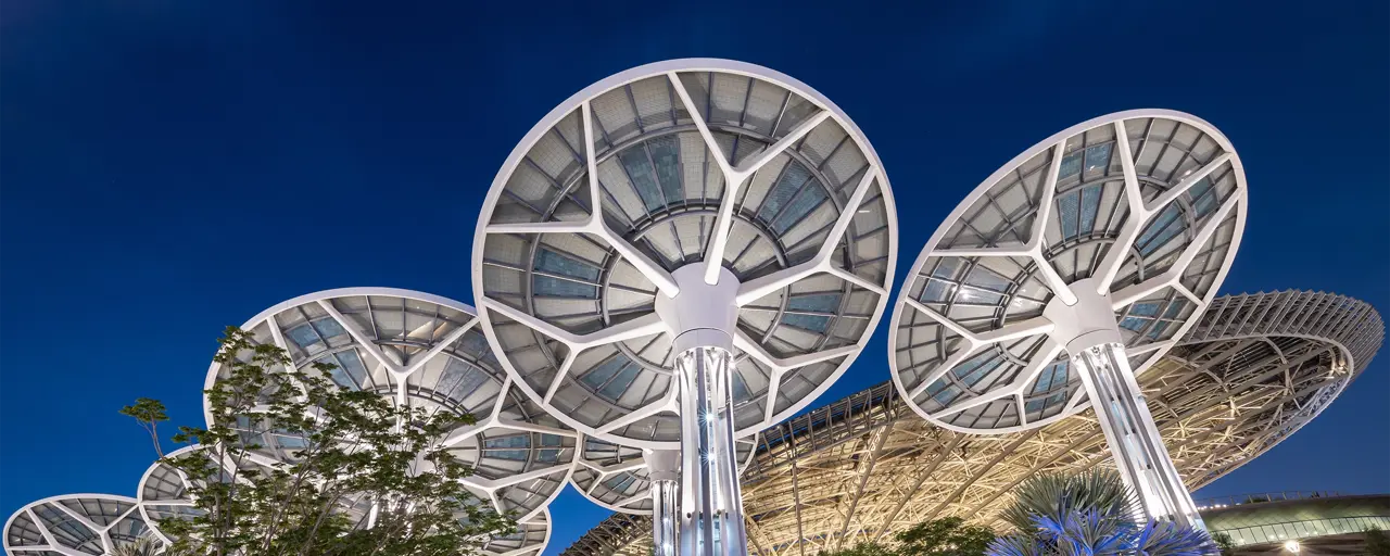 Multiple mushroom shaped solar panels against dark blue sky