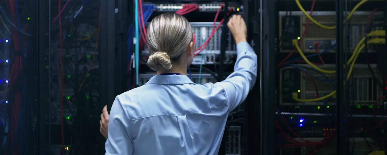 Woman in a data centre, reaching out for a cord