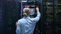 Woman in a data centre, reaching out for a cord