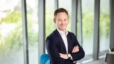 David Whysall, Global Managing Director of Energy and Natural Resources, smiling with his arms folded in an office with windows