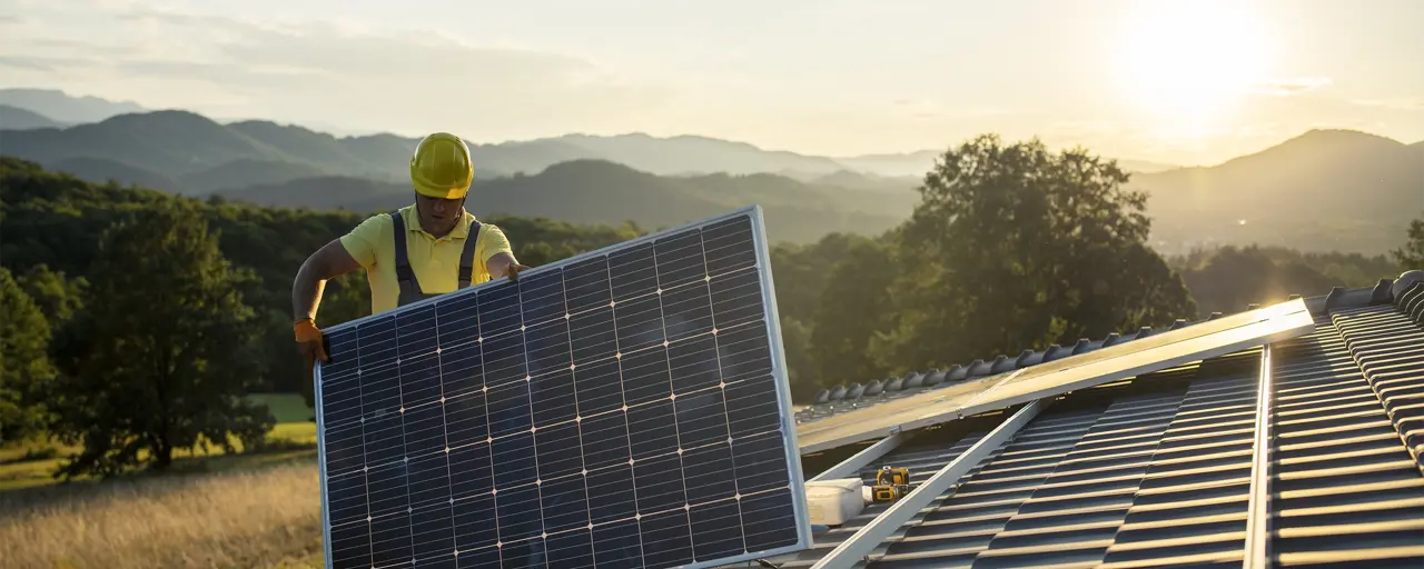 Construction worker fitting solar panel on roof