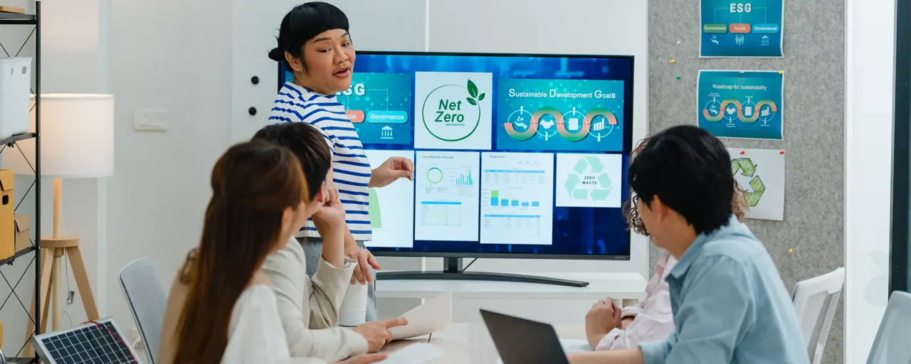 A group of coworkers discuss renewable energy solutions, emphasizing sustainable business practices in a modern office setting.