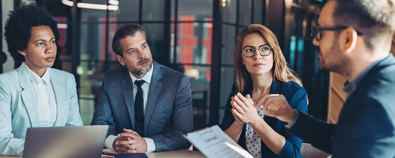 Four colleagues sat at a table in a meeting