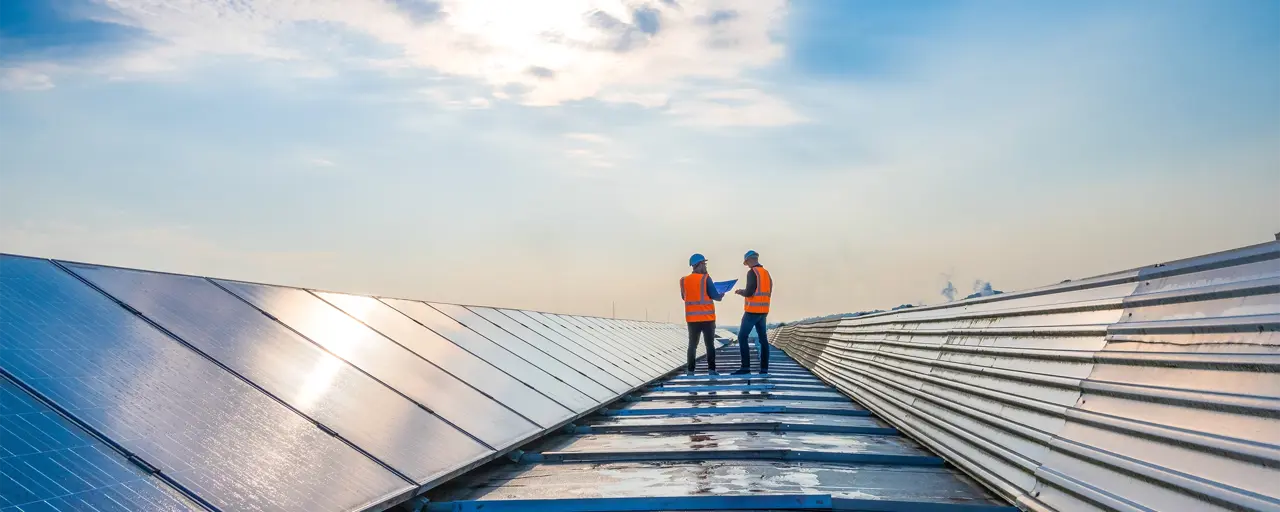 Two men in hi vis jackets standing on top of a solar panel farm