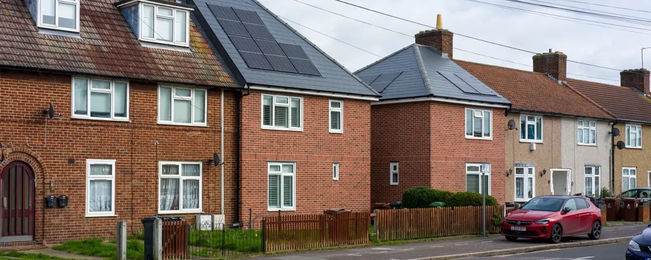 Brown houses on street with two houses that have solar panels on roof