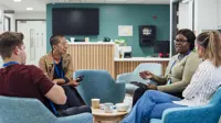 Four hospital workers sitting on blue chairs in a meeting 