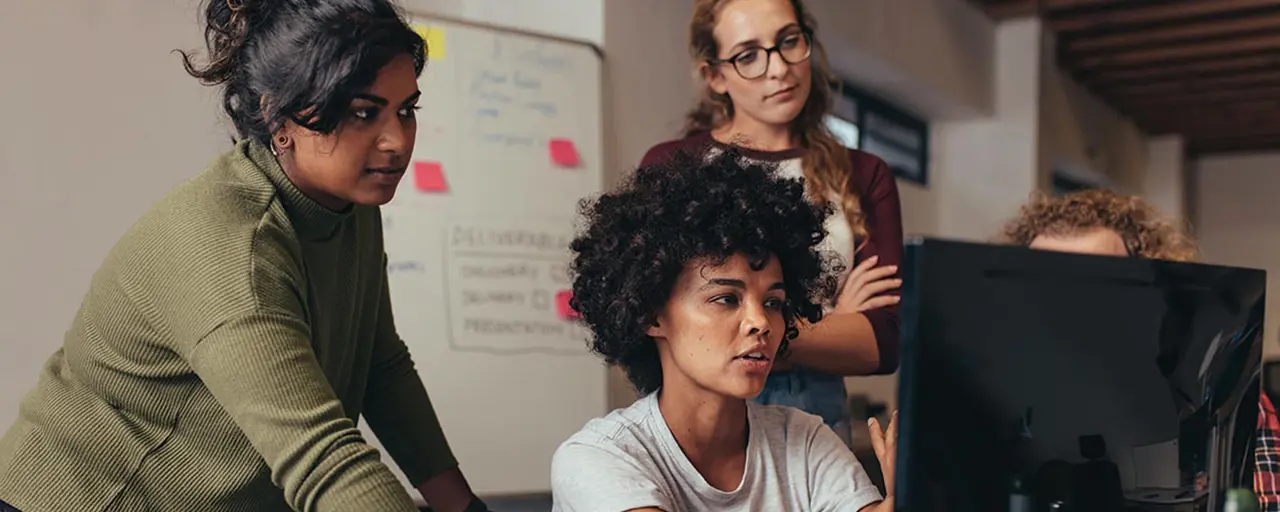 Three females huddled around computer