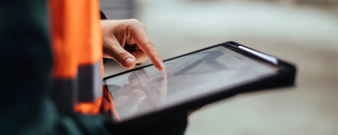 Person in orange hi vis vest using a digital tablet