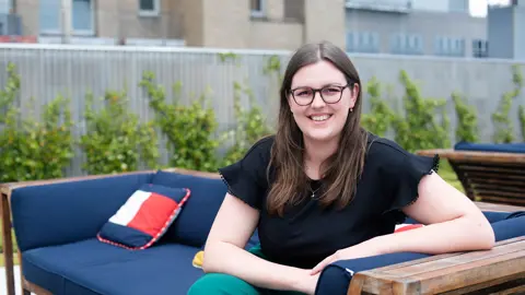 Director, Sustainability, US, Imogen Large, outside on armchair in front of trees