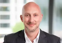 Portrait of James Hardy, Director, Head of UK Sustainability, standing in office space next to plant.