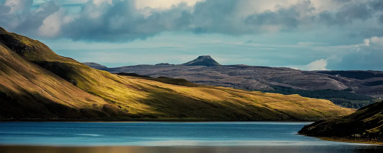 View of land and hills with the river reflecting the clouds and surrounding area