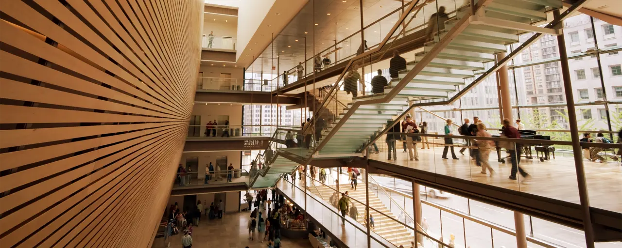 Interior of office building with wood panelling, glass stairs and workers