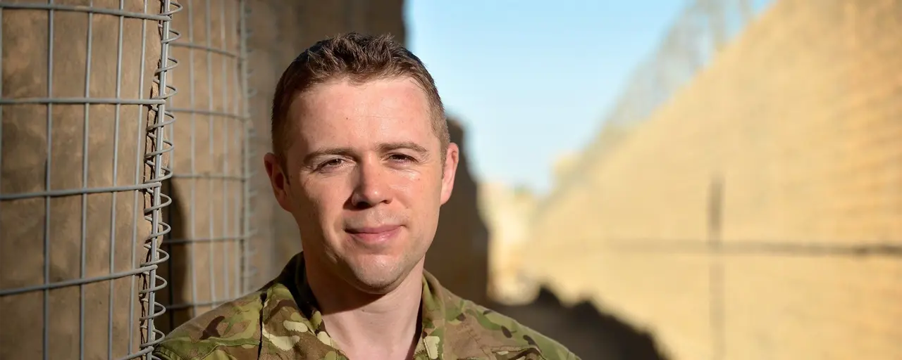 Portrait of a soldier smiling in uniform in a sandy landscape