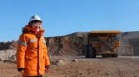 Woman in bright orange construction site uniform standing in a sandy landscape