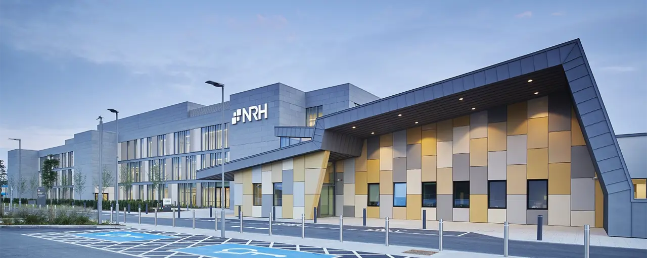 Big building with colourful yellow and grey square tiles with brand name NRH on it, and disabled parking outside