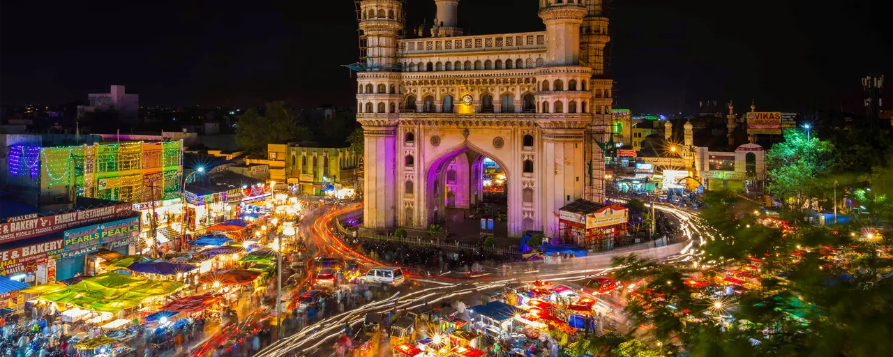 Long-exposure photo of traffic moving around the Charminar monument at night in the city of Hyderabad