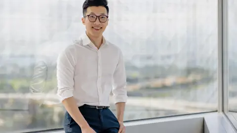 Portrait of Jia Jin Chin, Senior Cost Manager, Singapore, Standing against window pane.