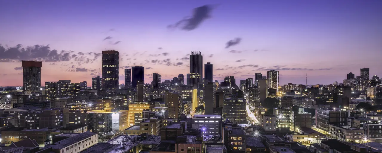 Sky view of skyscrapers in South Africa with sun setting in the dark