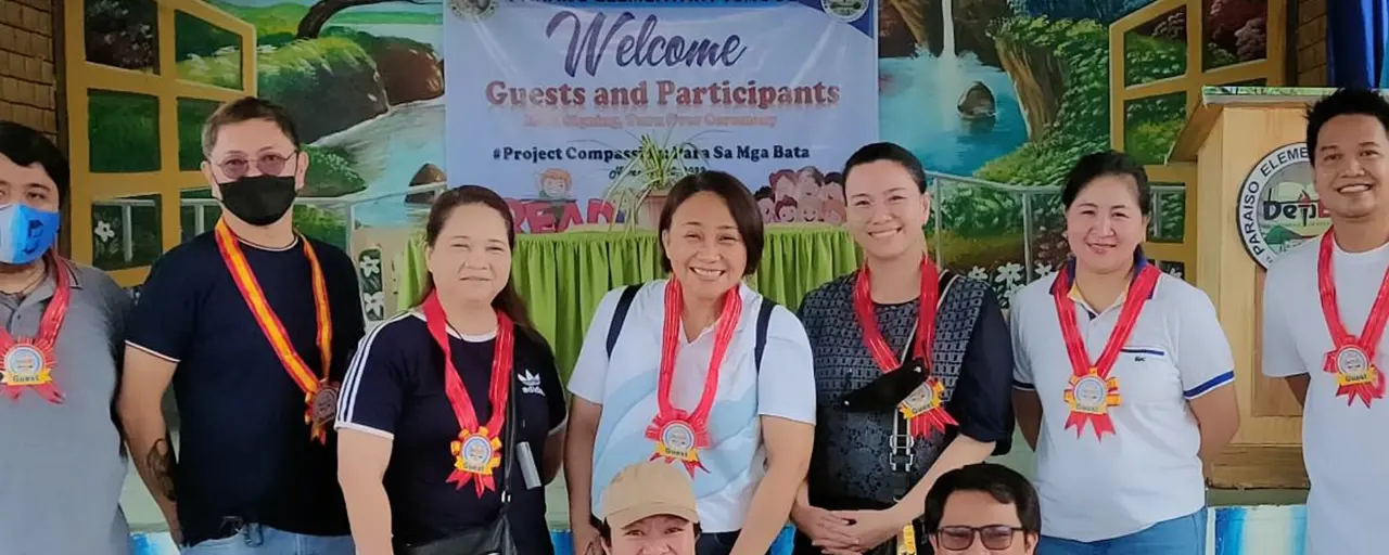 Group with medals around their necks smiling in front of welcome banner