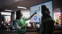 Two women in an office pointing at a screen with charts on it