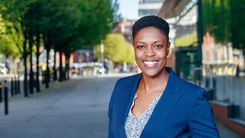 Portrait of Salisha Roberts, Senior Consultant, Cost Management, US, outside in front of street with trees.