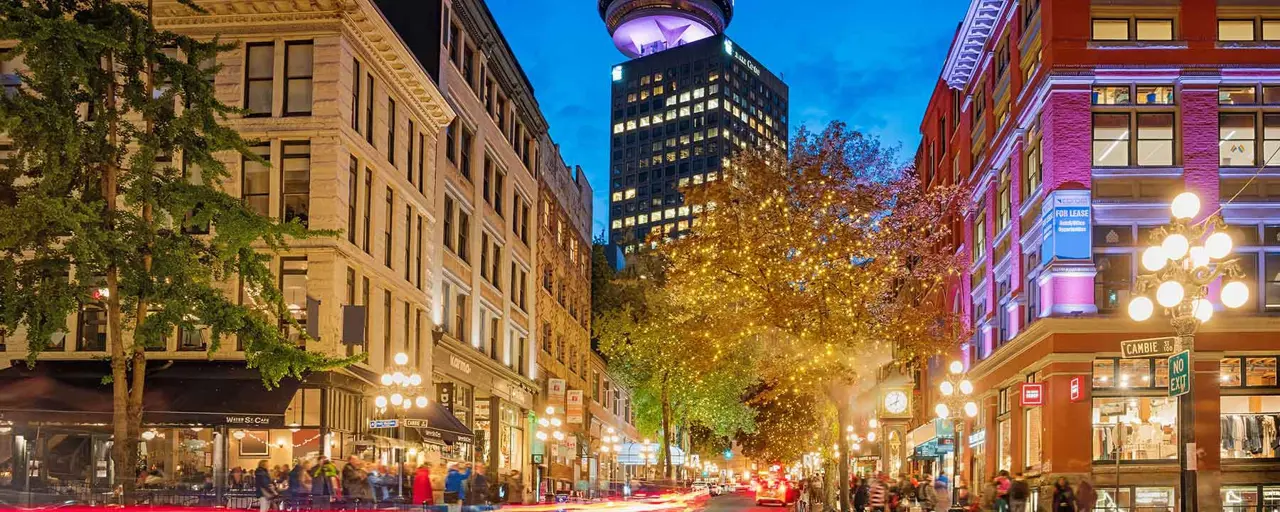 City view of Canada Tower in Toronto in the evening with skyscrapers beaming lights that light up the streets.