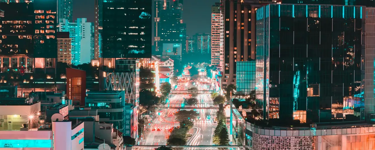 Singapore at night with glass skyscraper buildings and brightly lit roads with traffic