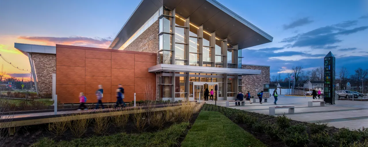 Exterior photo of a standalone library building with groups of people entering and exiting