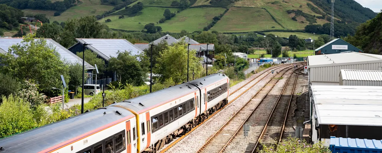 Train in a rural area, with green hill in the background