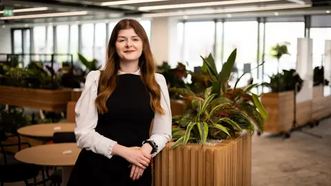 Portrait of Louise Gorringe, Senior Project Manager, Defence and Security, United Kingdom, Standing in office space against spikey plants.