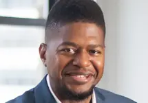 Wayne Lambert, Director of Supplier Diversity, Standing in office space against white background and glass window.