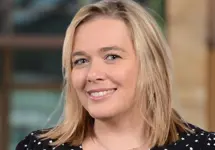 Wendy Cerutti, Head of Cost Management, Johannesburg, outside in front of a blurred brown background featuring a building and mix of natural and urban elements.