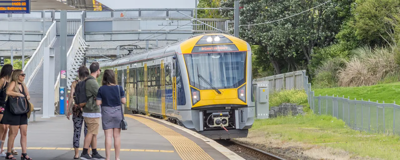 Yellow train entering a station with people waiting on the platform