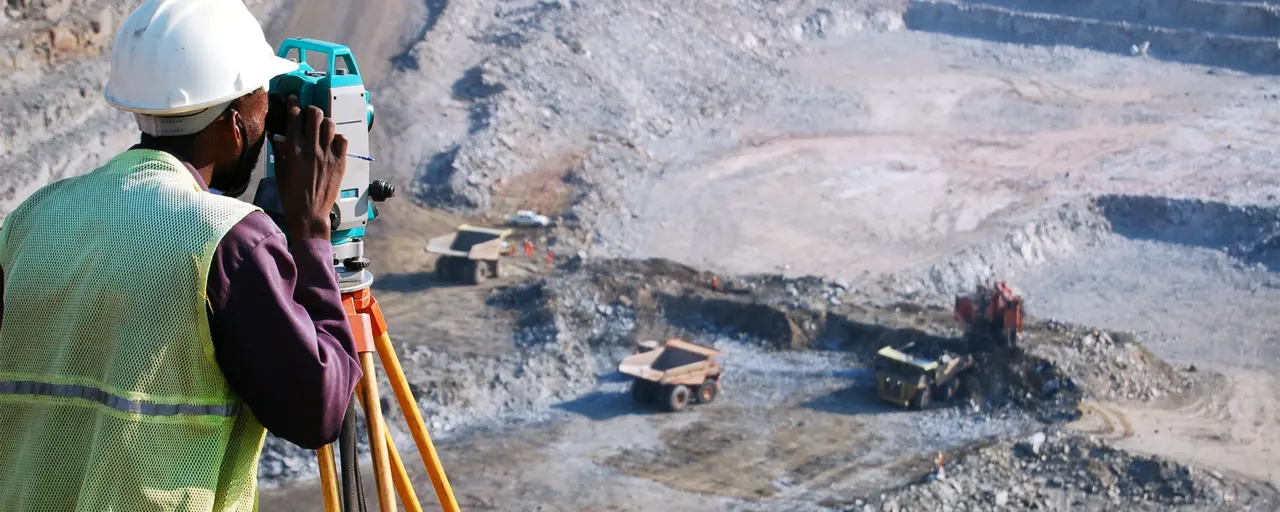 Builder looking into machine overlooking empty grovel construction site