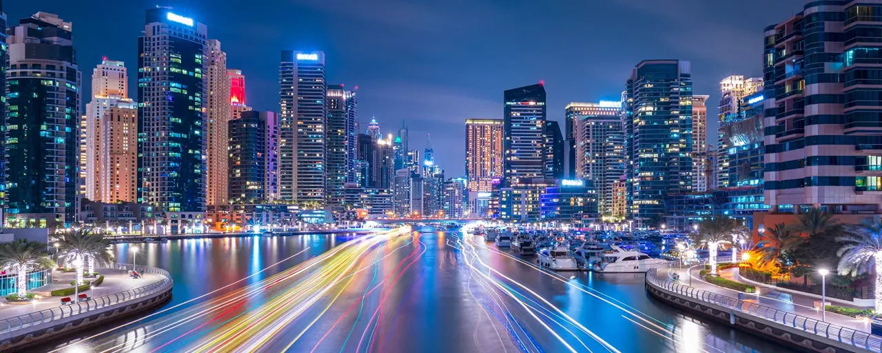 Skyscrapers at night alongside digitally imposed lines of colour on the water